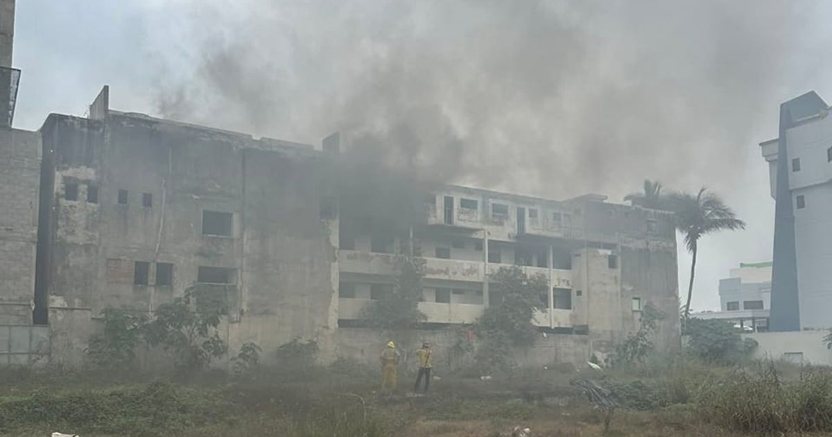 Bomberos trabajan para extinguir el incendio en un edificio en Mazatlán con humo saliendo de sus ventanas.