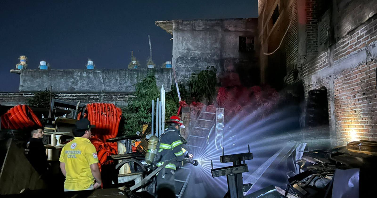 Escena nocturna de bomberos en acción apagando un incendio en bodega