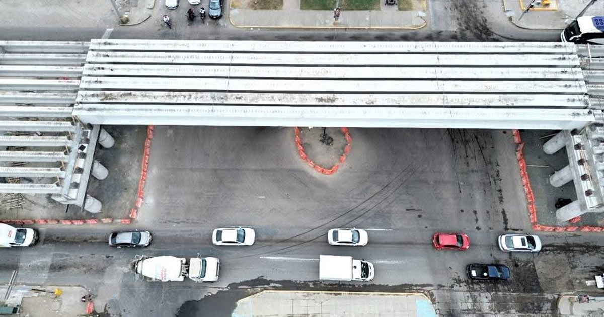 Vista aérea de la intersección en Mazatlán con estructura elevada y trabajos de construcción del puente vehicular norte, rodeada de tráfico y barreras naranjas.