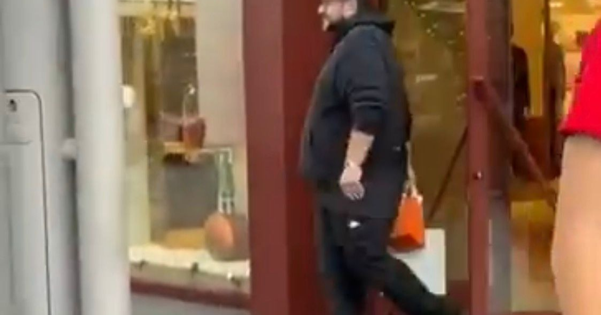 Hombre con bolsa naranja saliendo de tienda de lujo en Houston