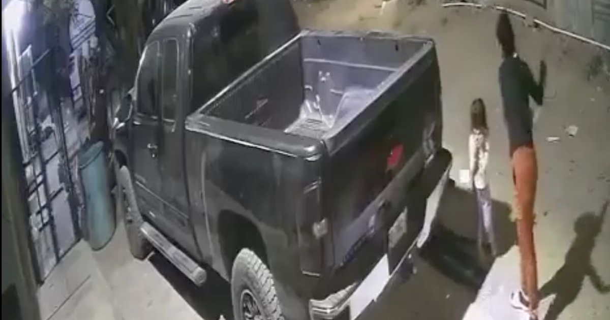 Camioneta negra estacionada con dos personas en un área residencial