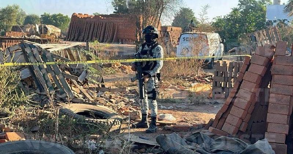 Escena forense en ladrillera de Culiacán con agente de seguridad, escombros y vehículo del SEMEFO.