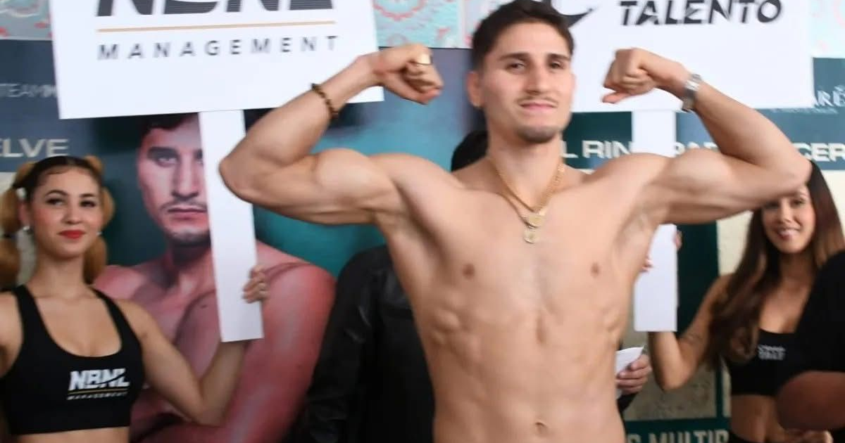 Marco Verde en pesaje con mujeres sosteniendo carteles y anuncios deportivos de fondo.