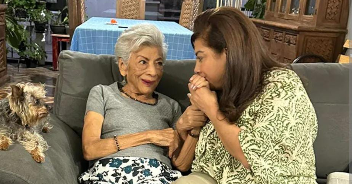 Clara Brugada y su madre, Margarita Molina Ríos, conversan sentadas en un sofá, con un perro Yorkshire al lado.