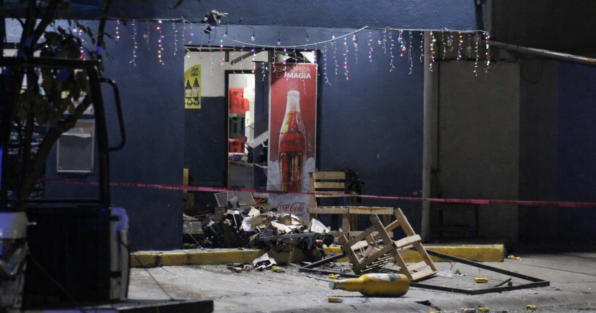 Puerta abierta de tienda en Mazatlán con escombros y cinta de advertencia tras ataque. Un cartel de Coca-Cola se ve al fondo.