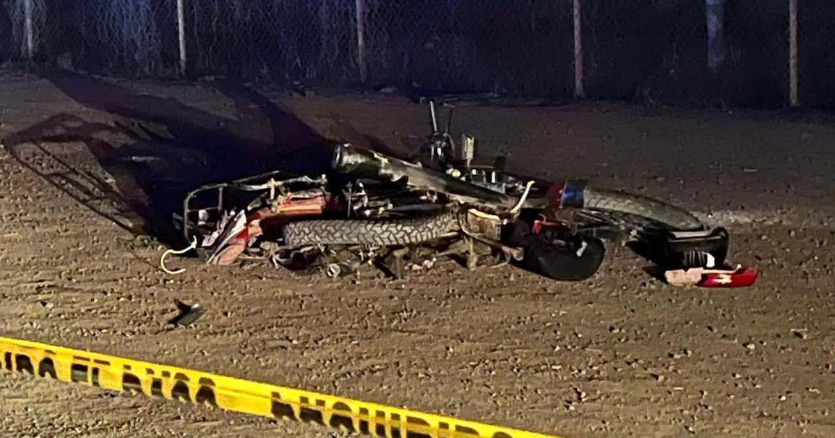 Motocicleta volcada en accidente vial nocturno con cinta de advertencia
