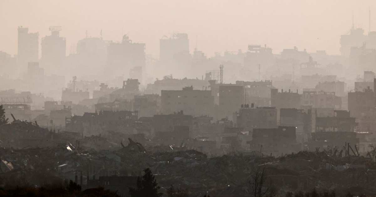 Paisaje urbano devastado en Gaza con edificios en ruinas tras conflicto y neblina densa.