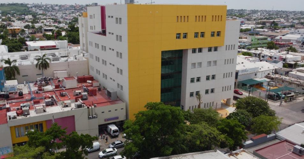 Edificio moderno blanco y amarillo en Culiacán rodeado de tráfico y árboles