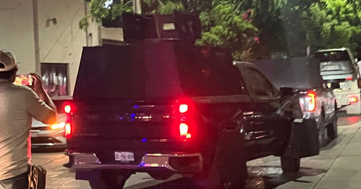 Camioneta robusta durante un operativo nocturno en Culiacán, con persona filmando y vegetación urbana.