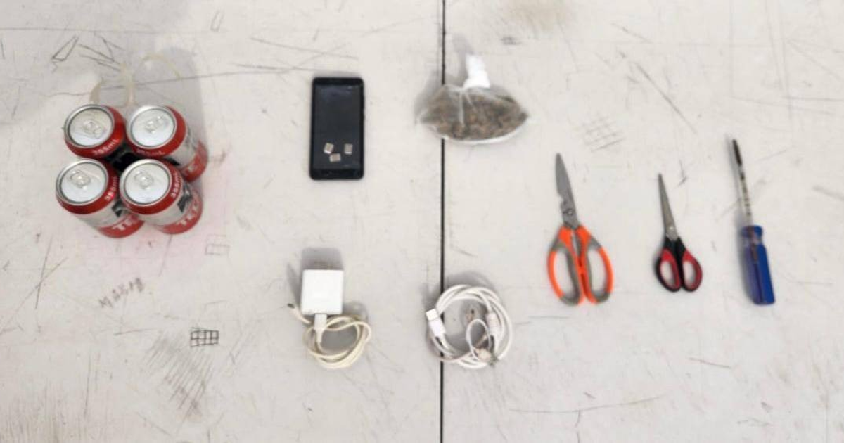 Mesa con latas de bebida, teléfono móvil, y objeto similar a hierba, asegurados en penal de Aguaruto.