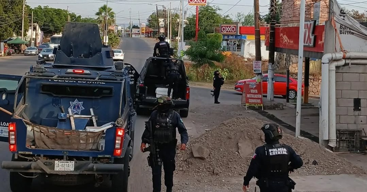 Operativo policial en calle urbana de Sinaloa durante festividades navideñas, con presencia de patrullas y oficiales armados.