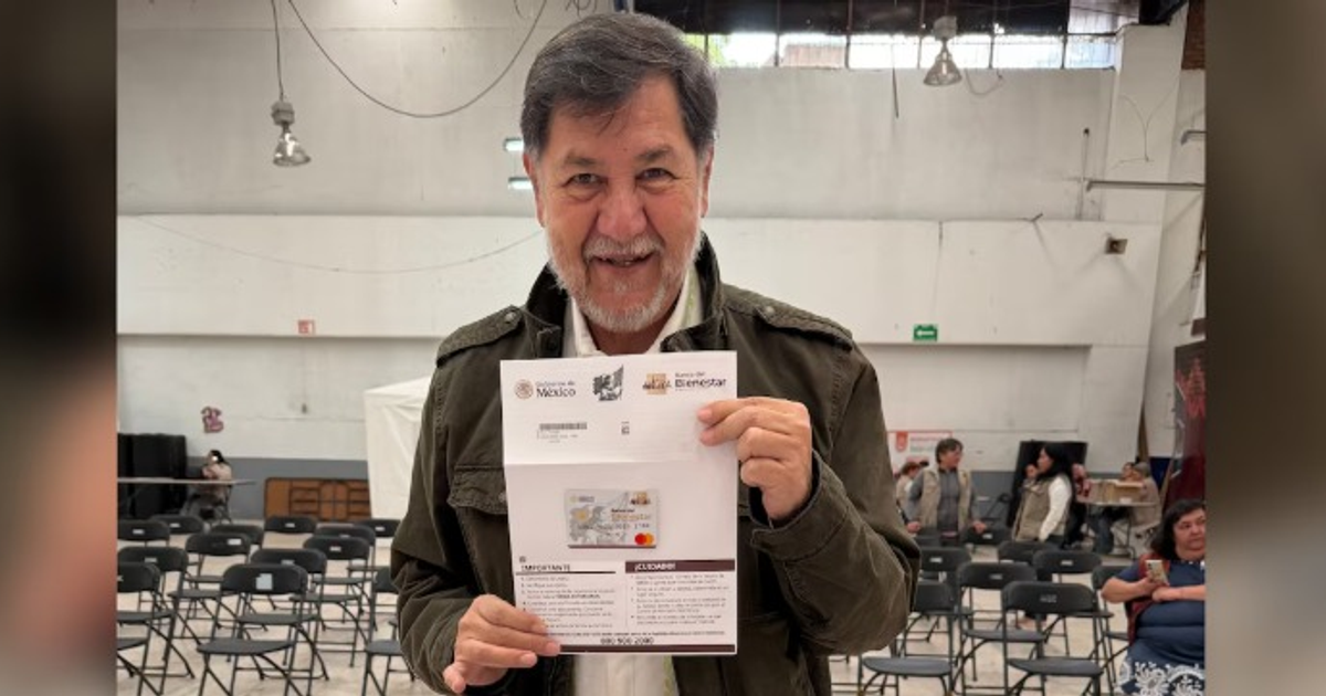 Gerardo Fernández Noroña sonriendo mientras sostiene su tarjeta de Pensión para el Bienestar en un evento público.
