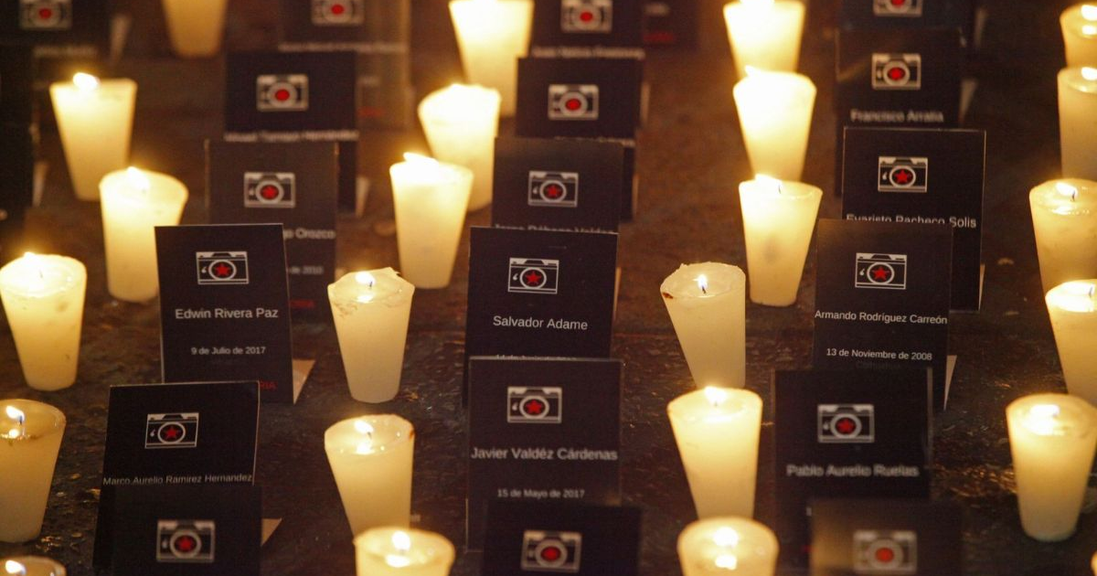 Velas encendidas en memoria de periodistas asesinados, con tarjetas con nombres y fechas de las víctimas.