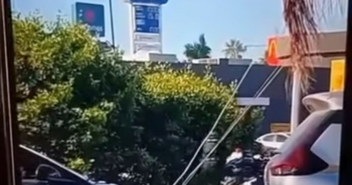 Paisaje urbano en Mazatlán con cartel publicitario y establecimiento de comida rápida.