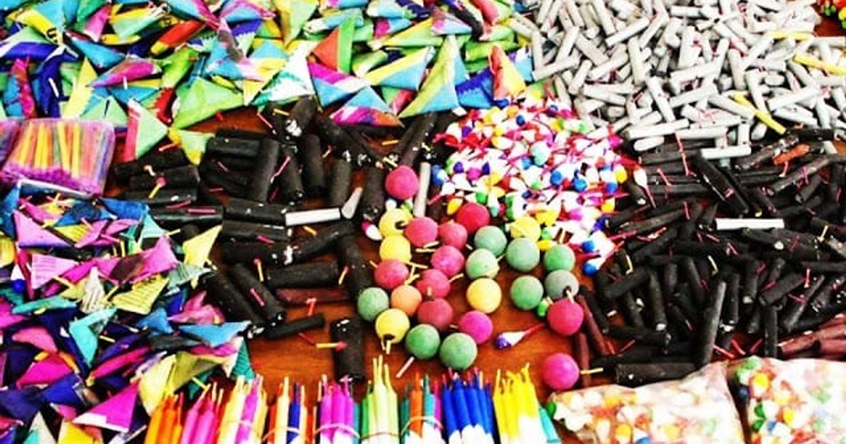 Variada selección de pirotecnia sobre una superficie, incluyendo formas triangulares, circulares y cilíndricas de colores vibrantes y oscuros.