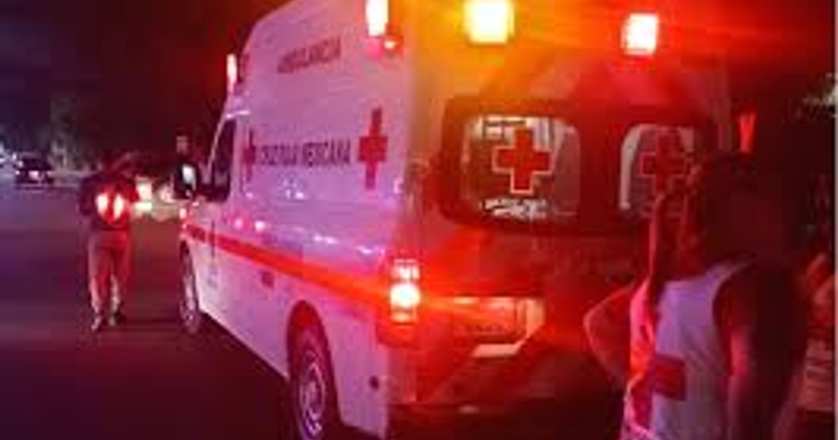 Ambulancia con luces de emergencia frente a una escena nocturna y personas alrededor, relacionada con un incidente de pirotecnia en Guasave