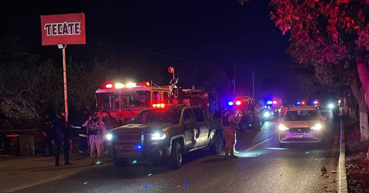Escena de emergencia nocturna en carretera con camión de bomberos y coches de policía en acción, vinculada a un incidente en Navolato, Sinaloa.