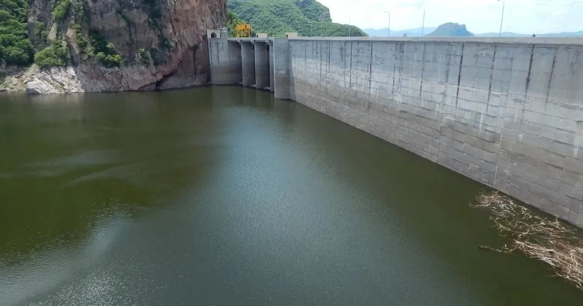Vista panorámica de una presa de concreto entre montañas verdes, relacionada con los niveles de almacenamiento de agua en Sinaloa por Conagua.