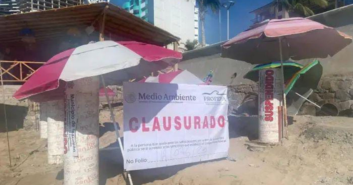 Sombrillas rojas y blancas en playa clausurada por Profepa en Mazatlán, Sinaloa