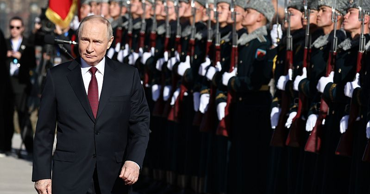 Vladimir Putin en un acto ceremonial militar en Moscú, rodeado de soldados en uniforme de gala que sostienen rifles.