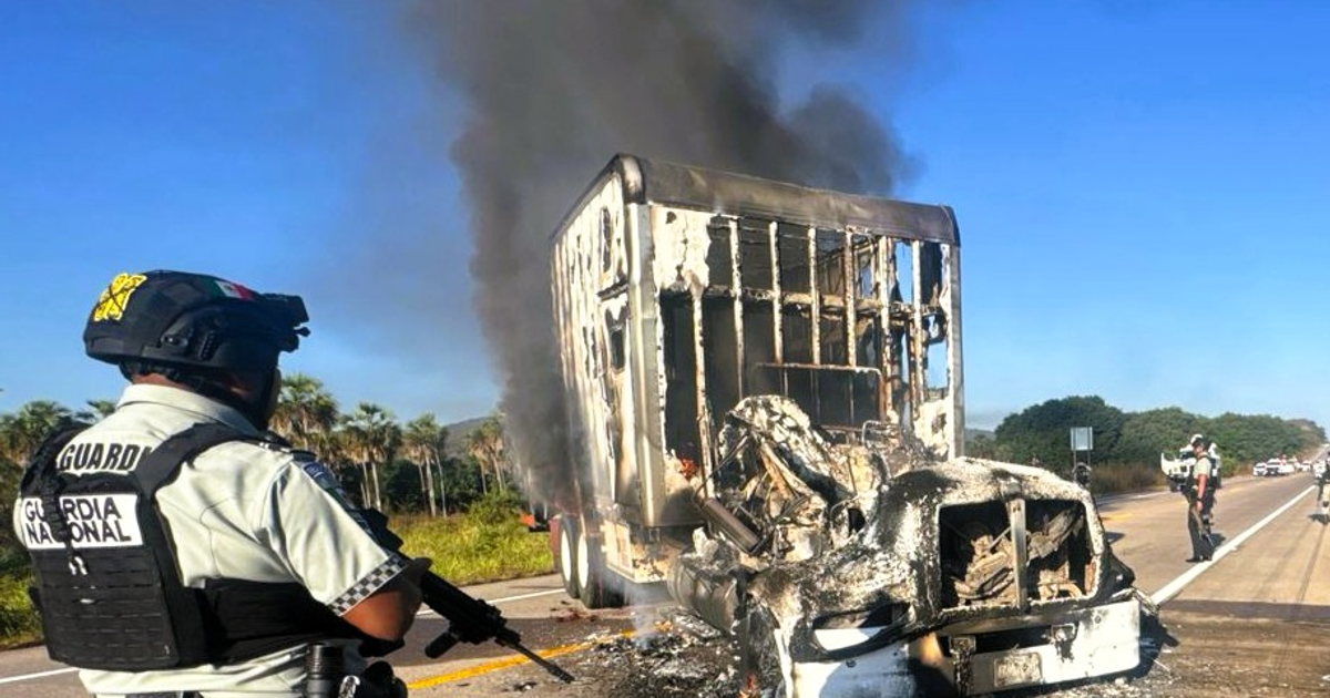 Camión en llamas observado por un agente de la Guardia Nacional en una carretera de Sinaloa