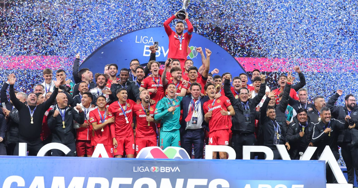 Los Diablos Rojos de Toluca celebran con alegría su bicampeonato en el Apertura 2025, sosteniendo el trofeo rodeados de confeti y un cartel de LIGA BBVA.