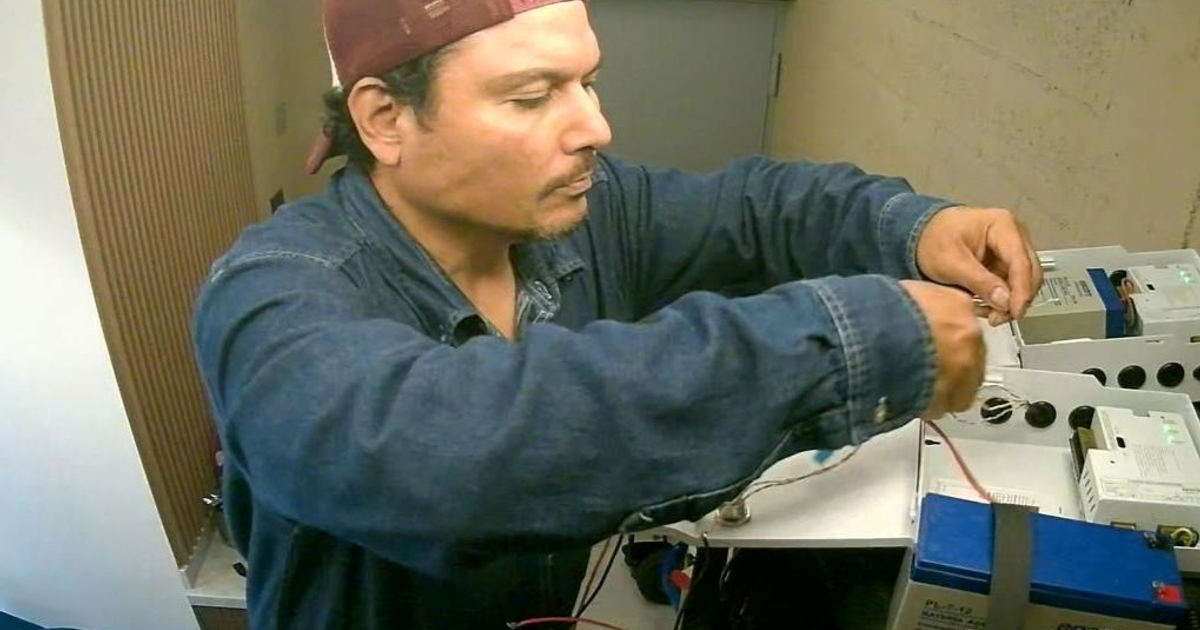 Hombre manipulando equipos eléctricos en entorno laboral