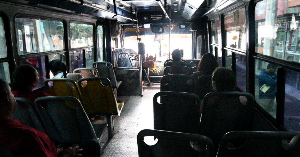 Pasajeros dentro de un autobús en Culiacán, con asientos ocupados y algunos vacíos, bajo luz tenue.