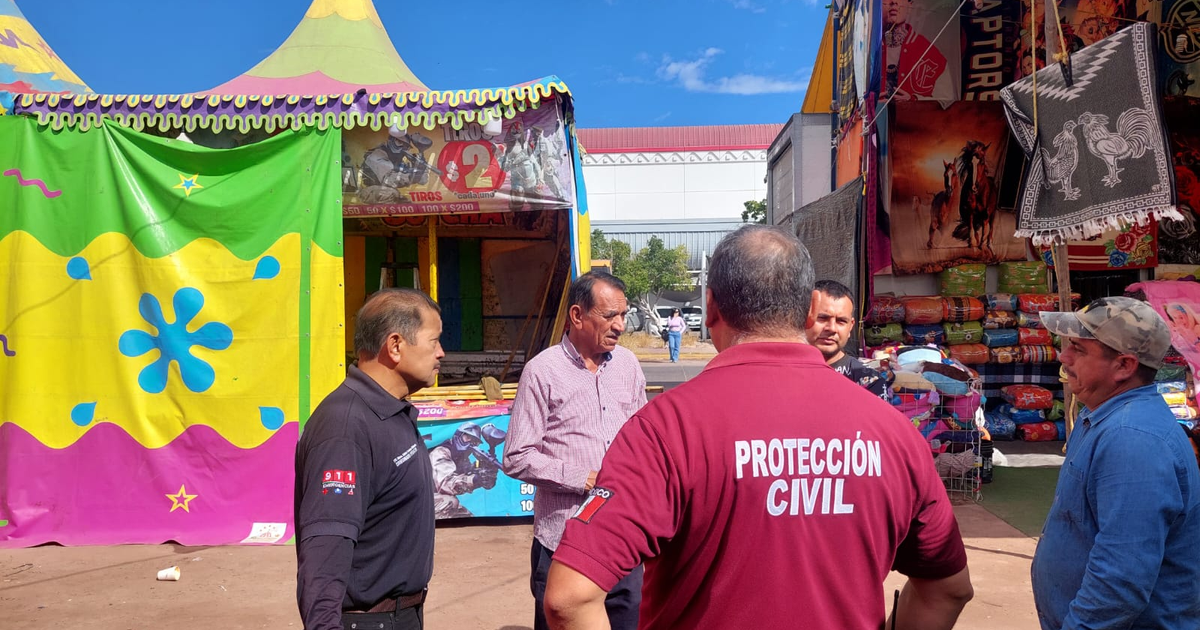 Personas en la Verbena de Los Mochis 2025, bajo toldos coloridos con un oficial de Protección Civil presente.