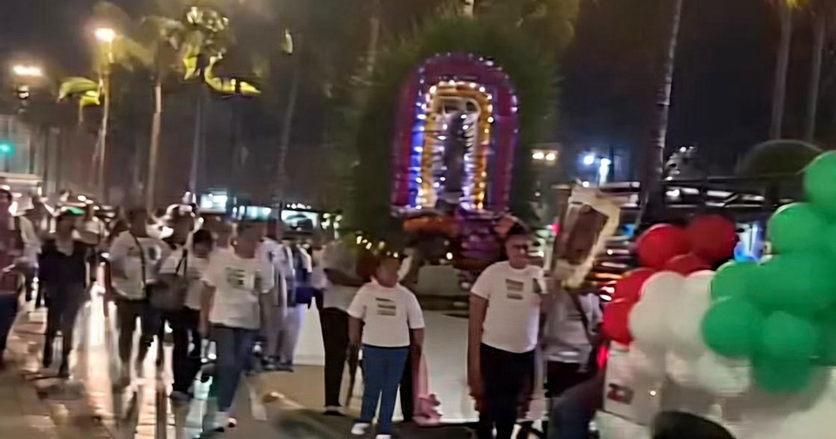 Procesión nocturna en el Malecón de Mazatlán con decoraciones iluminadas y globos tricolores por el Día de la Virgen.