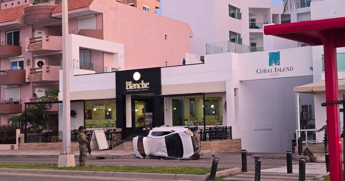 Automóvil volcado frente al restaurante Blanche en Avenida del Mar; un soldado presente y edificios urbanos al fondo.