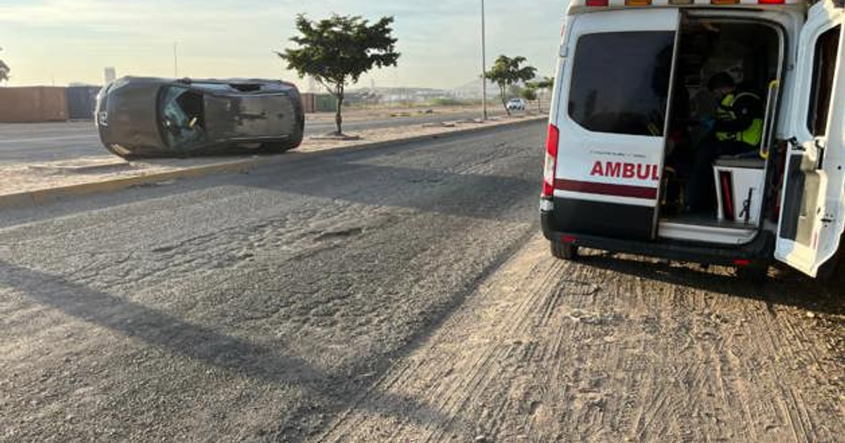 Vehículo volcado sobre carretera en Ahome, Sinaloa, con ambulancia asistiendo cerca.
