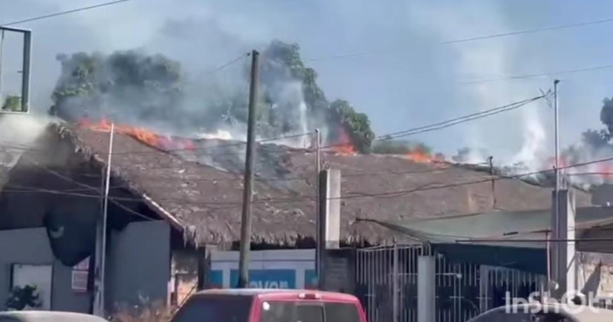 Techo en llamas tras explosión en bodega de Escuinapa, con vehículos en el primer plano y humo denso en el aire.