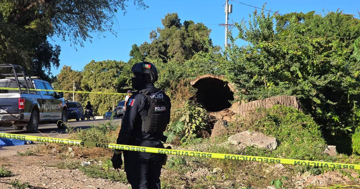 Policía vigilando escena del crimen en Navolato, acordeonada con cinta de precaución.