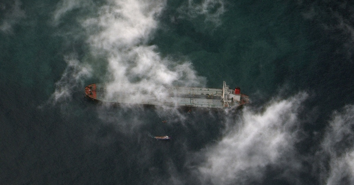 Barco de carga rodeado de nubes y pequeñas embarcaciones en el mar, conectado al bloqueo marítimo de Venezuela denunciado por la ONU.
