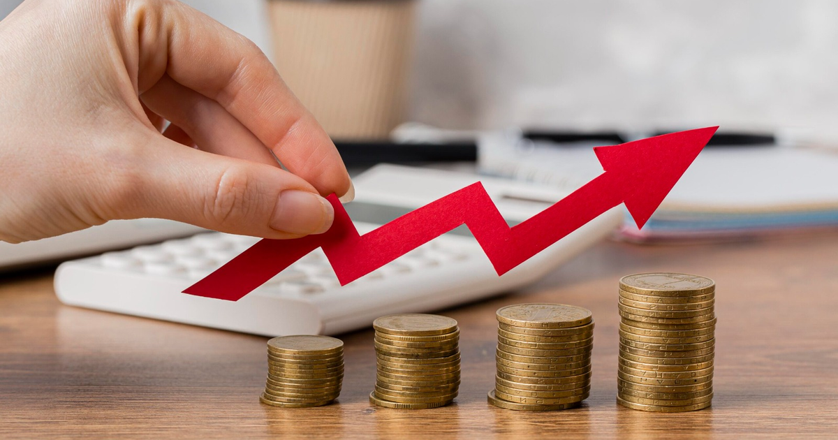 Mano con flecha roja simbolizando crecimiento económico sobre monedas, representando el aumento al salario mínimo de 2026.