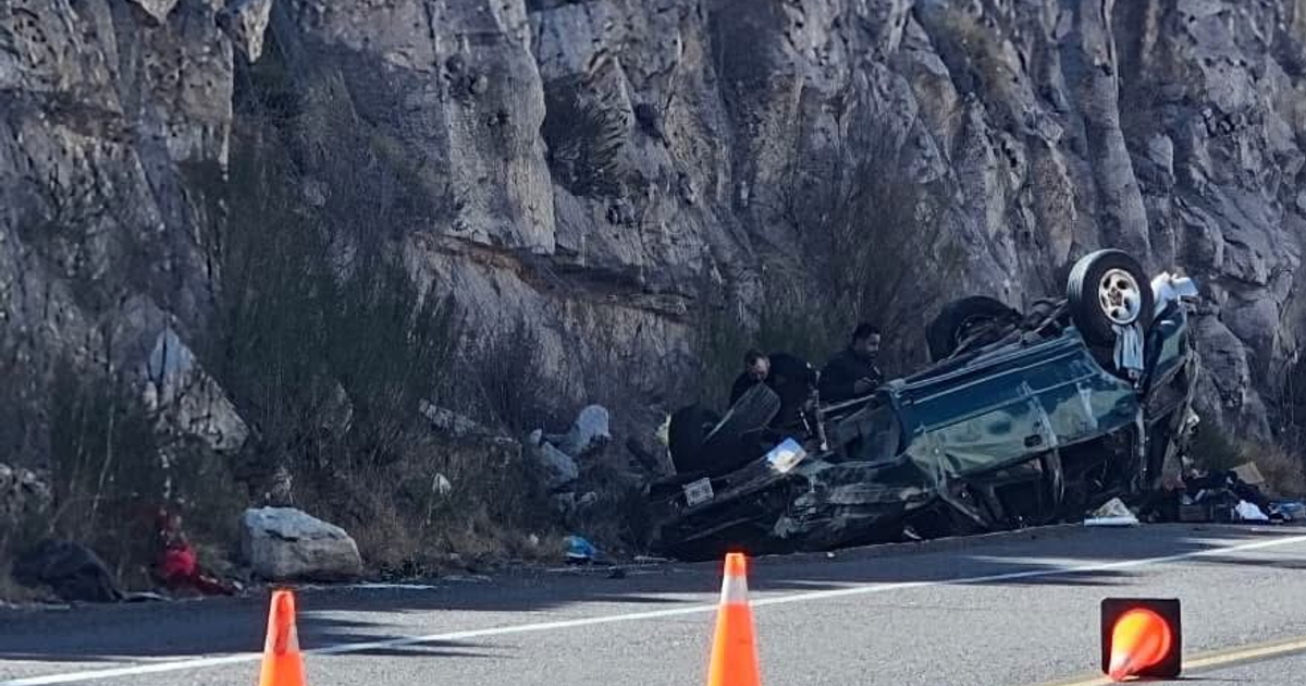 Vehículo volcado en accidente en la Supercarretera Durango-Mazatlán, rodeado de personas y conos de tráfico, cerca de un desértico acantilado.