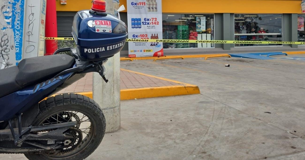 Motocicleta policial en estacionamiento acordonado, tienda al fondo durante investigación de crimen en Culiacán.