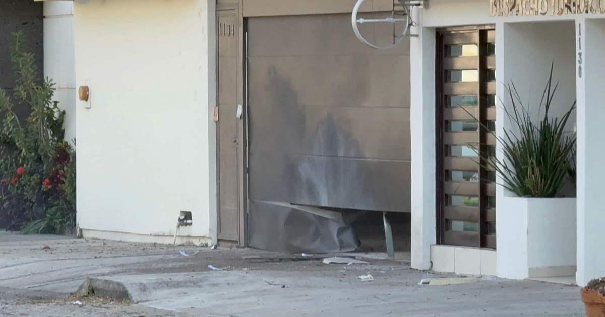 Puerta de garaje dañada en casa de Culiacán tras explosión en la colonia Las Quintas.