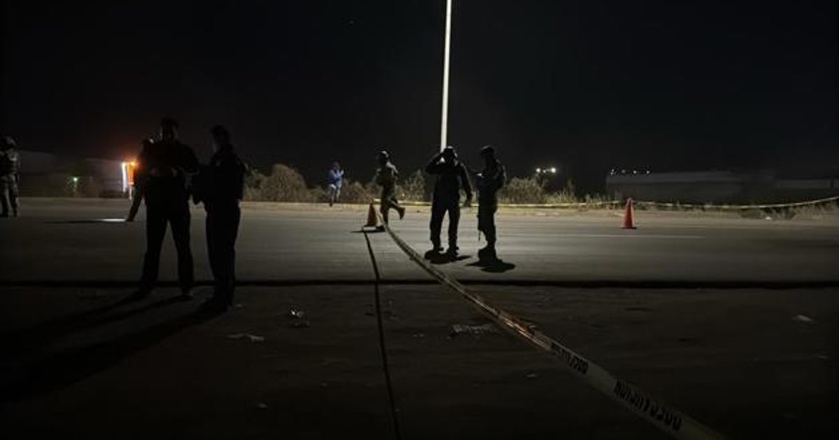 Agentes de seguridad trabajan en una escena forense nocturna en Culiacán junto a un cono de tráfico.