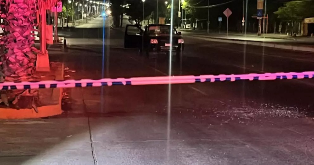 Calle de Culiacán con cordón de seguridad, coche dañado y escombros en el pavimento, tras un tiroteo nocturno.