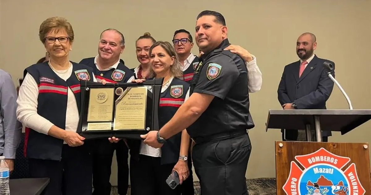 Grupo sosteniendo una placa durante la ceremonia de aniversario del Cuerpo de Bomberos de Mazatlán