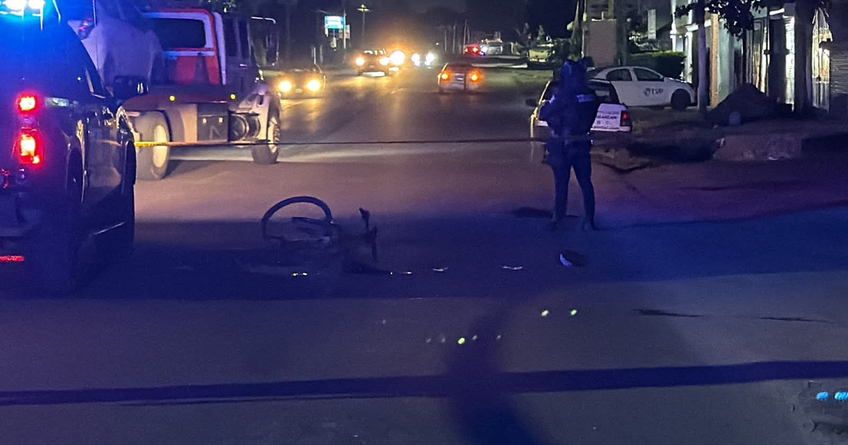 Escena nocturna de investigación policial en Bellavista con auto de policía, camión, bicicleta caída y cinta amarilla