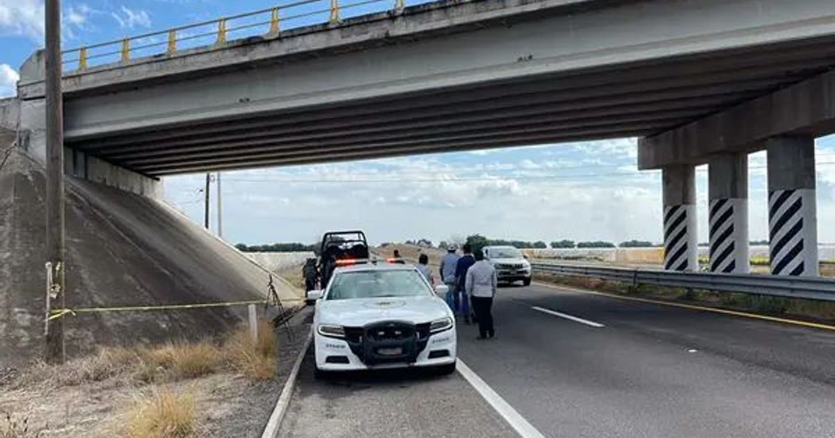 Vehículo policial estacionado bajo un puente en Navolato, Sinaloa. Investigan hallazgo de cuerpo decapitado, zona acordonada.