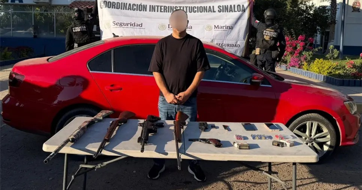 Hombre frente a un auto rojo con armas incautadas y autoridades de fondo en Culiacán