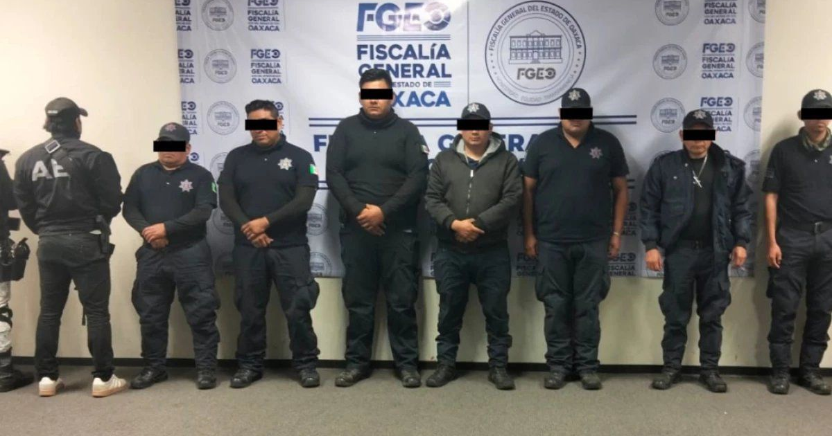 Policías detenidos frente al logo de la Fiscalía de Oaxaca