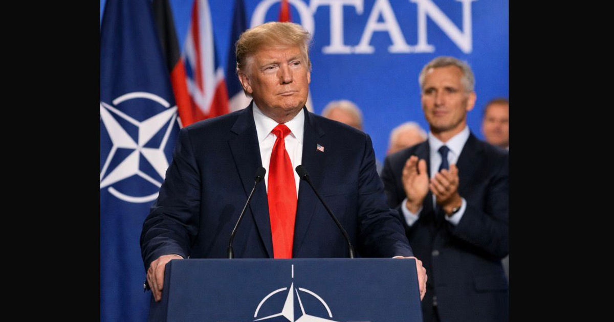 Hombre en evento de la OTAN en Davos, con fondo de banderas y gráficos, en contexto de acuerdos sobre Groenlandia y el Ártico.