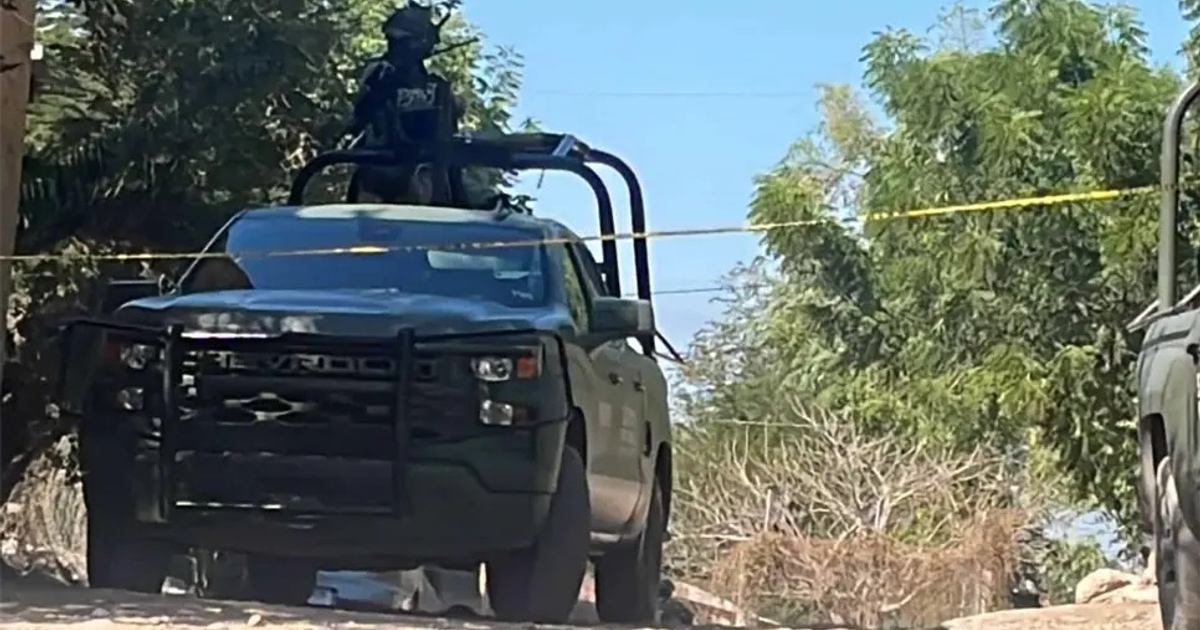 Camioneta oscura con reja de protección y persona vestida tácticamente cerca de un panteón en Navolato