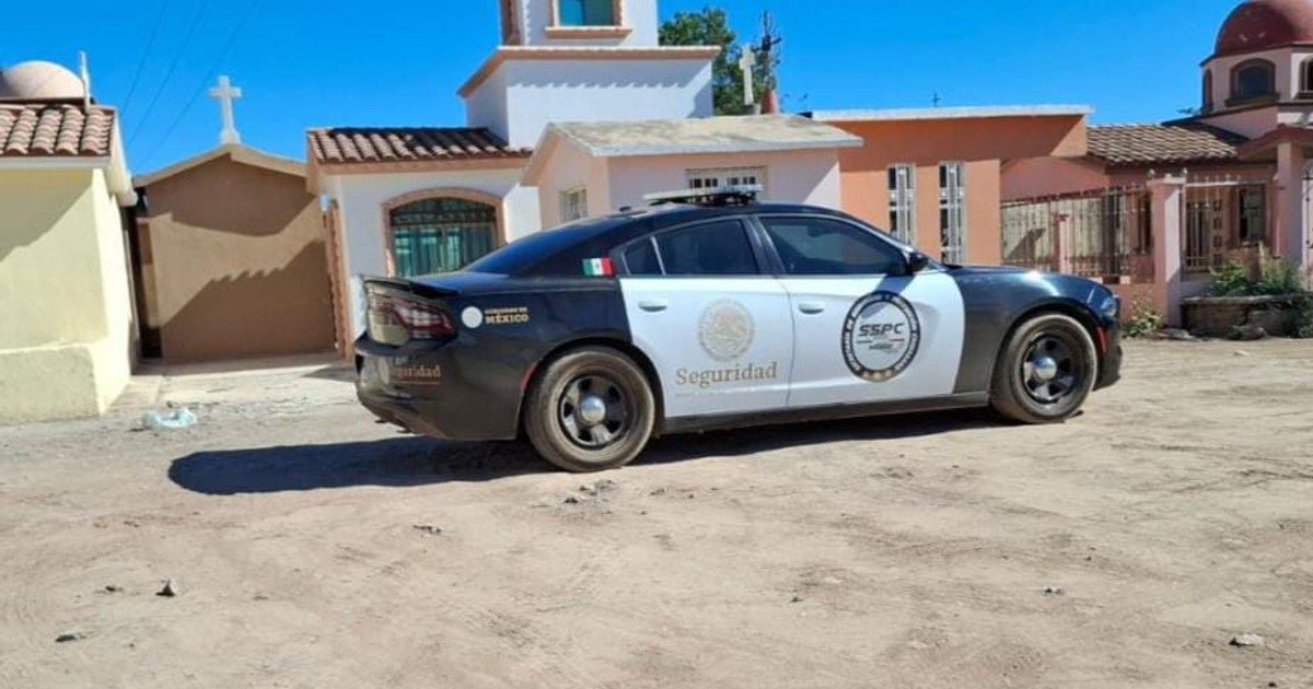 Auto de policía blanco y negro estacionado con insignias de seguridad en Navolato