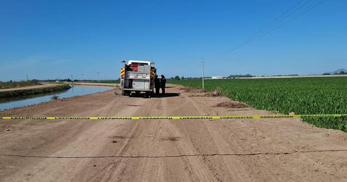 Camión de emergencias en canal Rosales, Navolato, con campos de cultivo al fondo y cinta de emergencia visible.